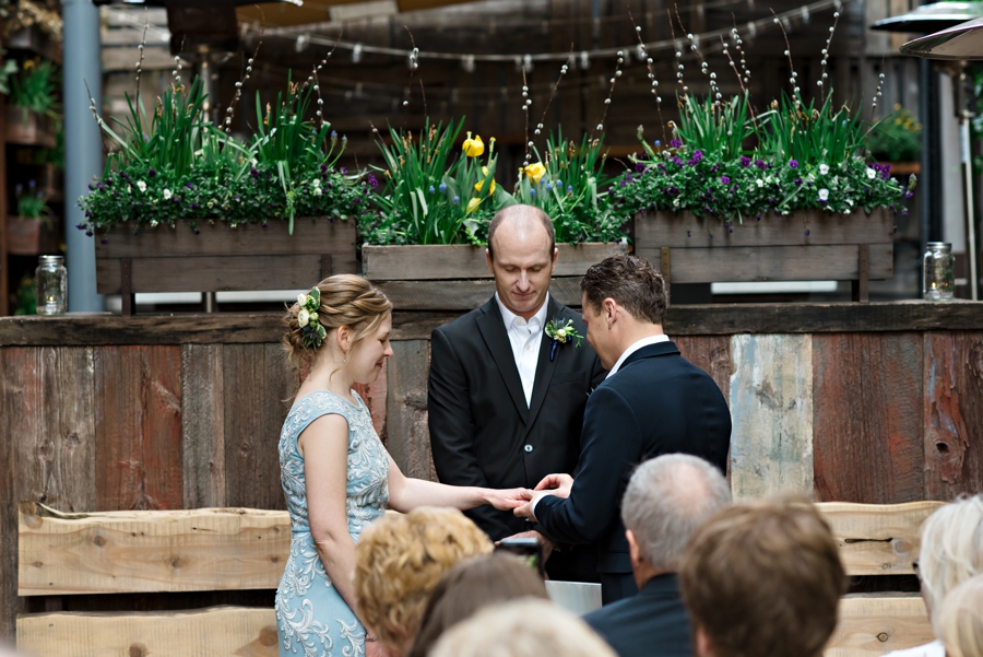 A groom places a wedding ring on his bride.